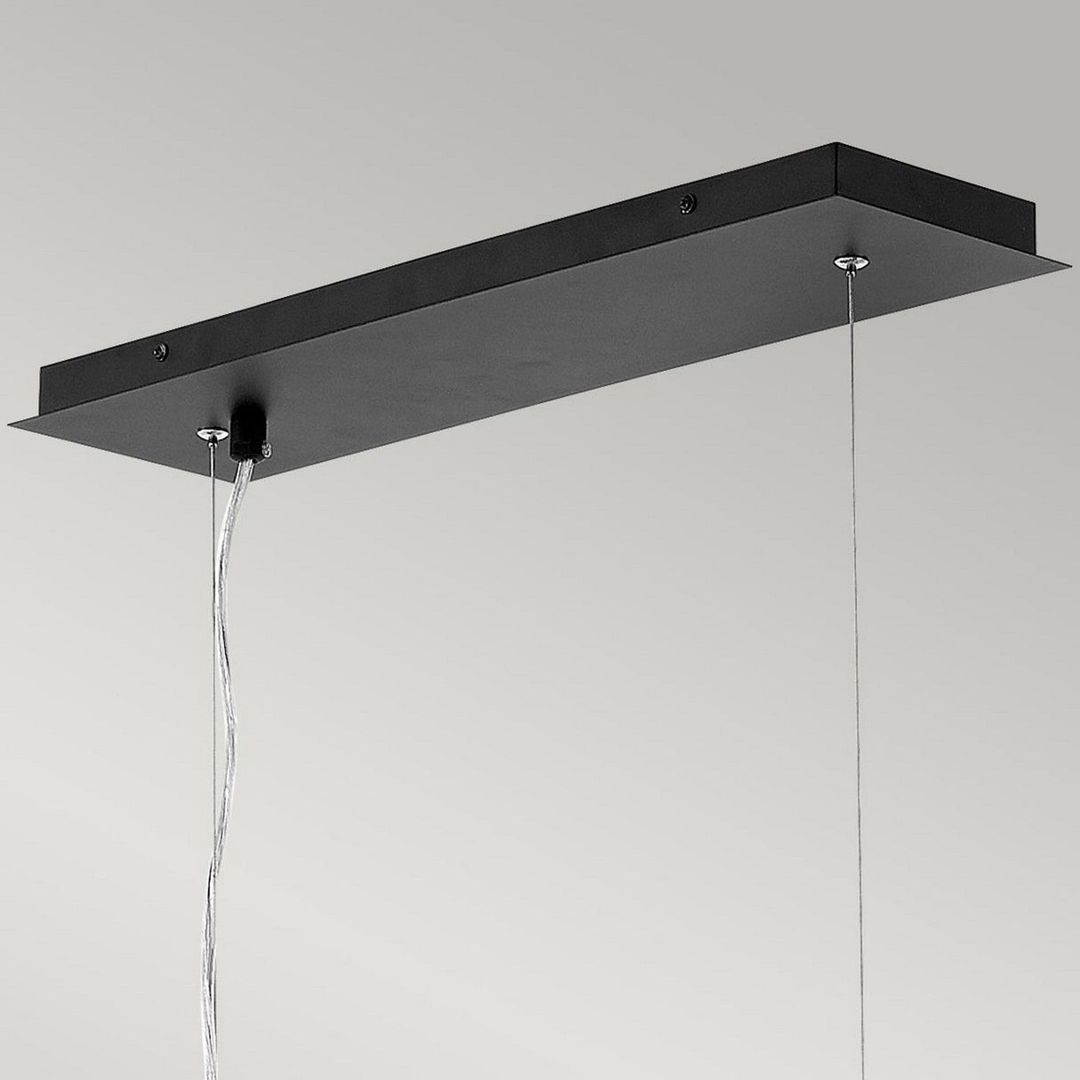 Introducing the Zuma 6 Light Linear Chandelier in Satin Black/Gold: a rectangular black metal ceiling light fixture with two cables for hanging. Its sleek, modern design showcases geometric elements, perfectly set against a plain gray background.