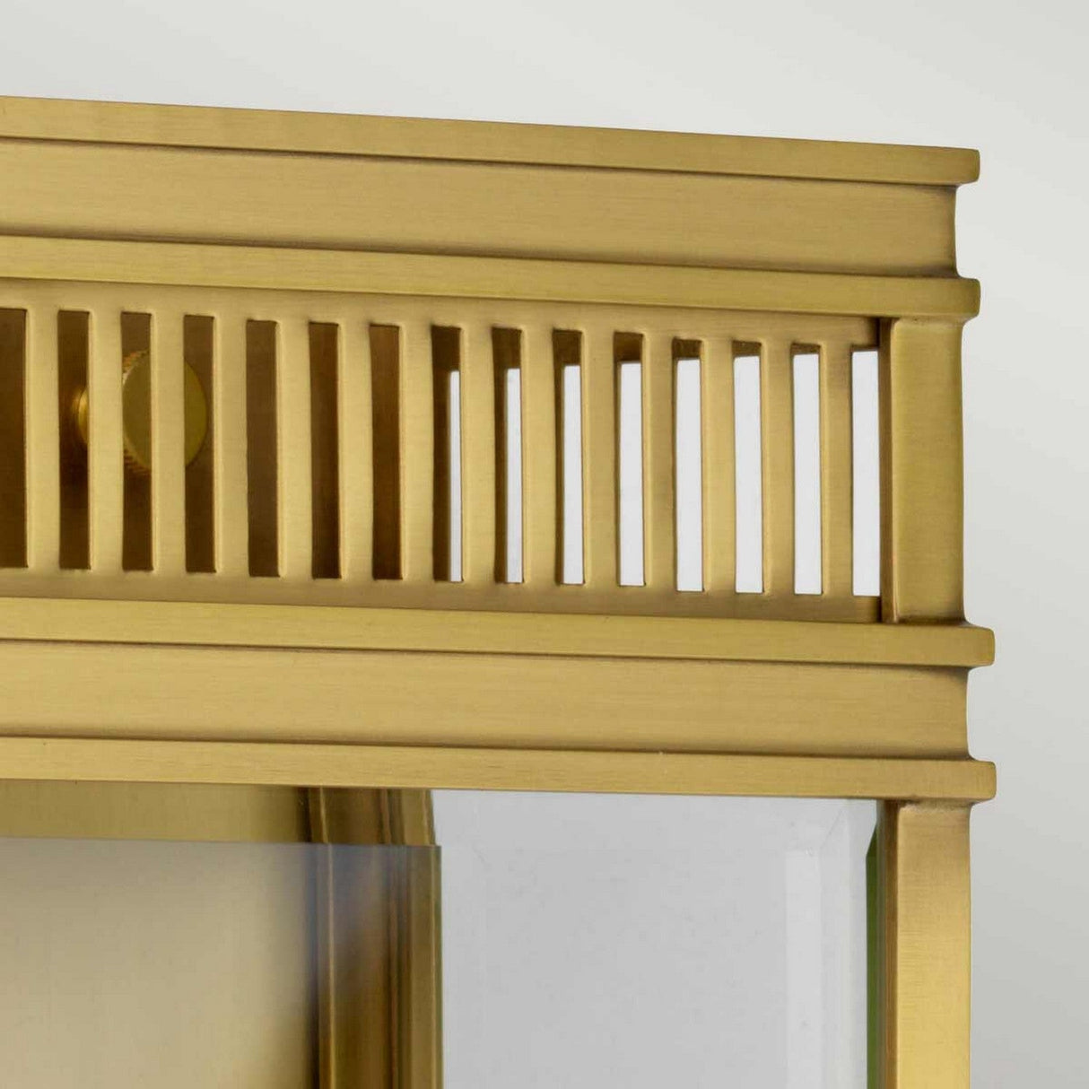 A close-up of the Holborn 2 Light Outdoor Wall Light in brushed brass showcases a stylish architectural detail featuring vertical slats and a rectangular top. The design evokes a Georgian-inspired aesthetic, set against a light background, making it ideal for an outdoor wall light.