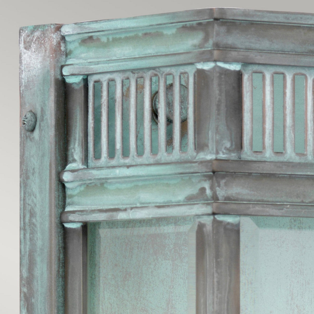 Close-up of the Holborn 2 Light Outdoor Wall Light in Verdigris finish, showcasing its weathered and decorative metal structure. The design includes vertical slits and intricate corner elements, exhibiting signs of aging and corrosion. The neutral background accentuates the texture and color of the solid brass construction.