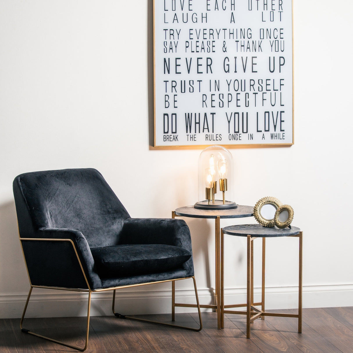 Hill Interiors Set of 2 Gold and Black Marble-Effect Side Tables styled beside a navy velvet armchair with a glass dome lamp and framed wall art.