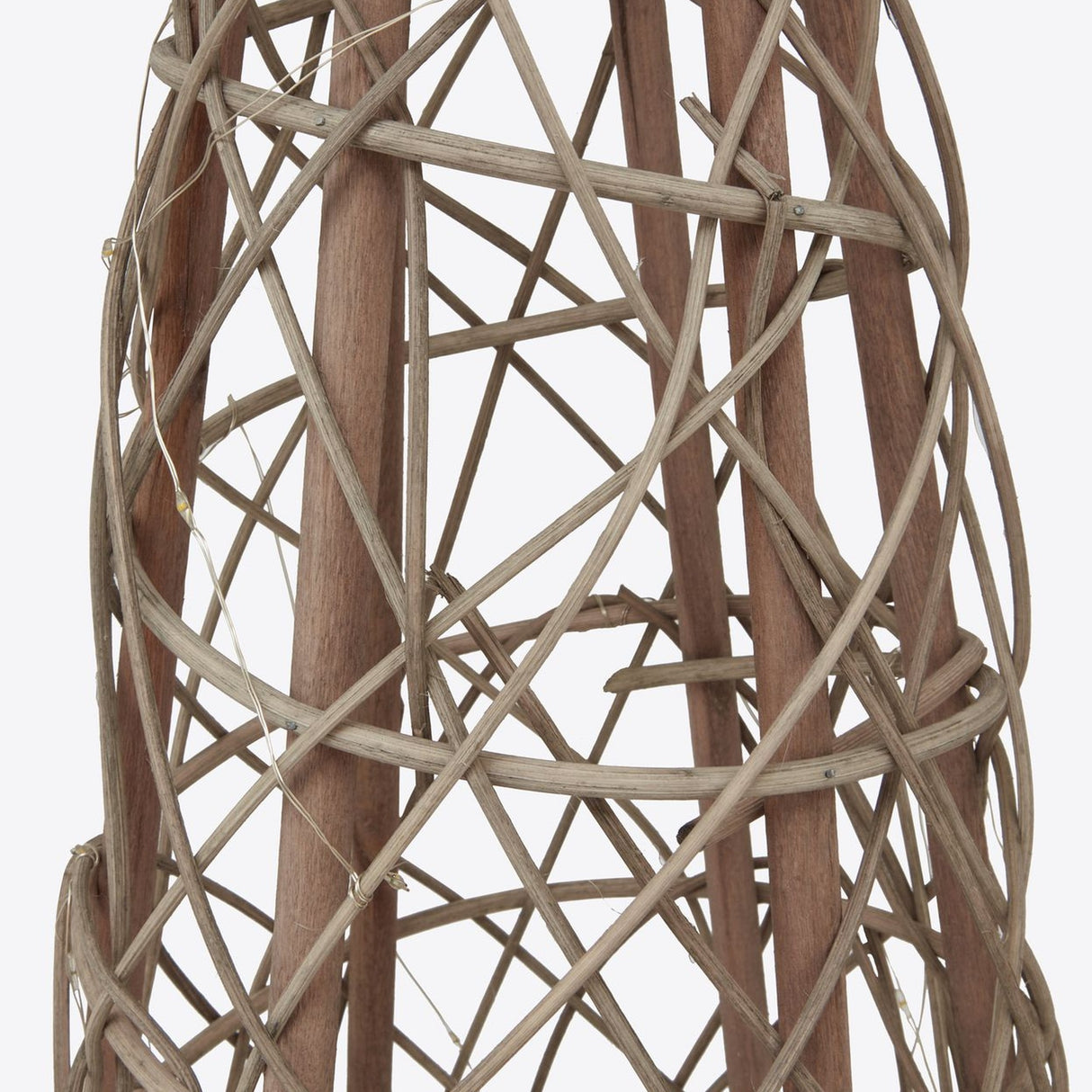 Close-up of the Hill Interiors small LED wicker Christmas tree in brown, showing the woven strands, wooden poles, and threaded fairy lights.