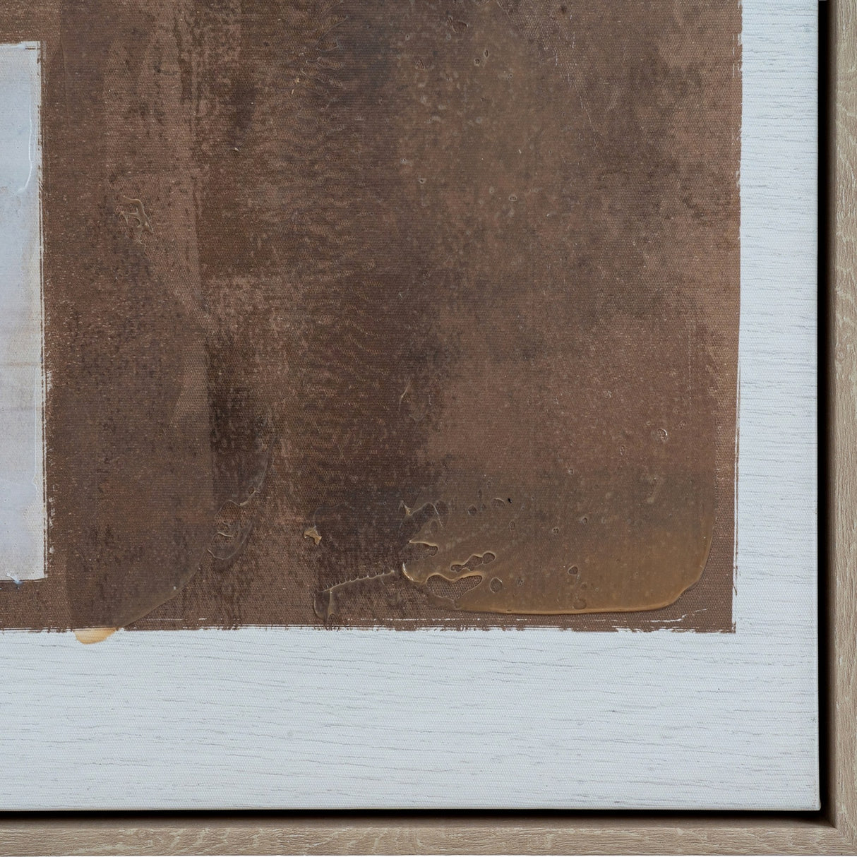 Close-up of Hill Interiors hand painted canvas wall art showing textured brown brushwork with glossy amber accents within a white wooden frame edge.