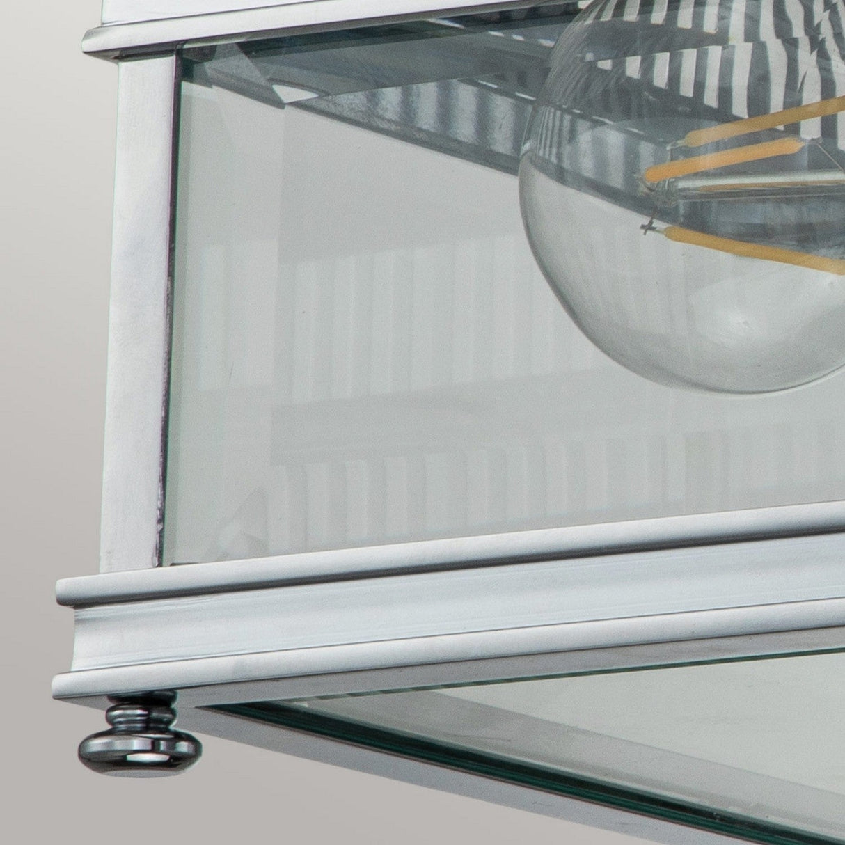 Close-up of the Holborn 2 Light Outdoor Flush in polished chrome, showcasing its modern glass and metal design featuring a visible round bulb. The fixture’s clean lines and reflective surface create a subtle striped pattern from room reflections, making it ideal for both indoor and outdoor lighting applications.