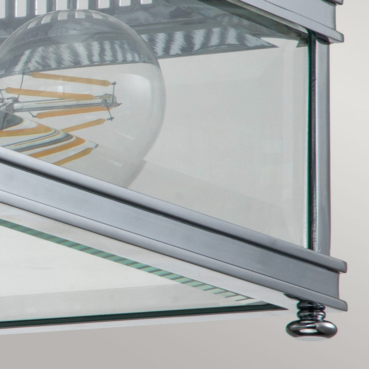 Close-up of the Holborn 2 Light Outdoor Flush, featuring a modern ceiling light fixture with a clear glass casing and polished chrome accents. The exposed bulb with its visible filament enhances the reflective interior elements, making it ideal for IP44 outdoor lighting applications.