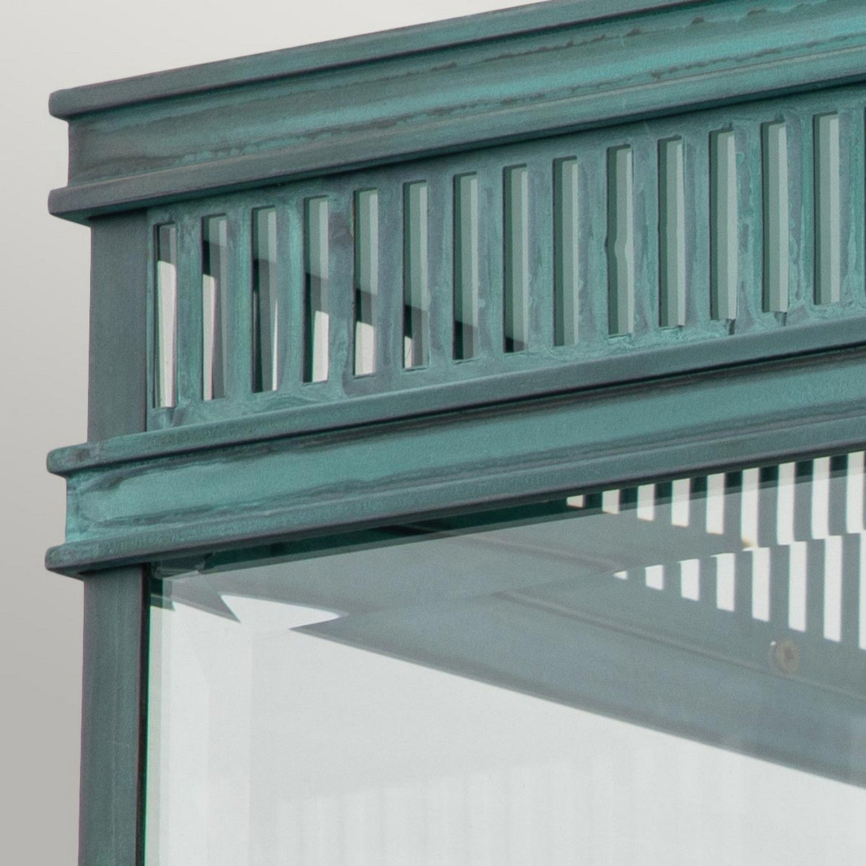 Close-up of the Holborn 2 Light Outdoor Flush in a verdigris finish, featuring a teal-colored metal frame with vertical slats and clear glass panels beneath. The structure exudes a vintage-inspired appearance against a light background.
