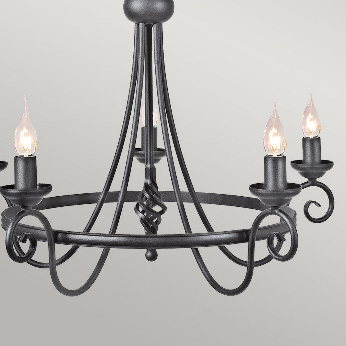 The Harlech 5 Light Chandelier - Black captures a medieval-inspired allure, showcasing its black wrought iron structure with five curving arms that each hold a candle-style light fitted with flame-shaped bulbs.