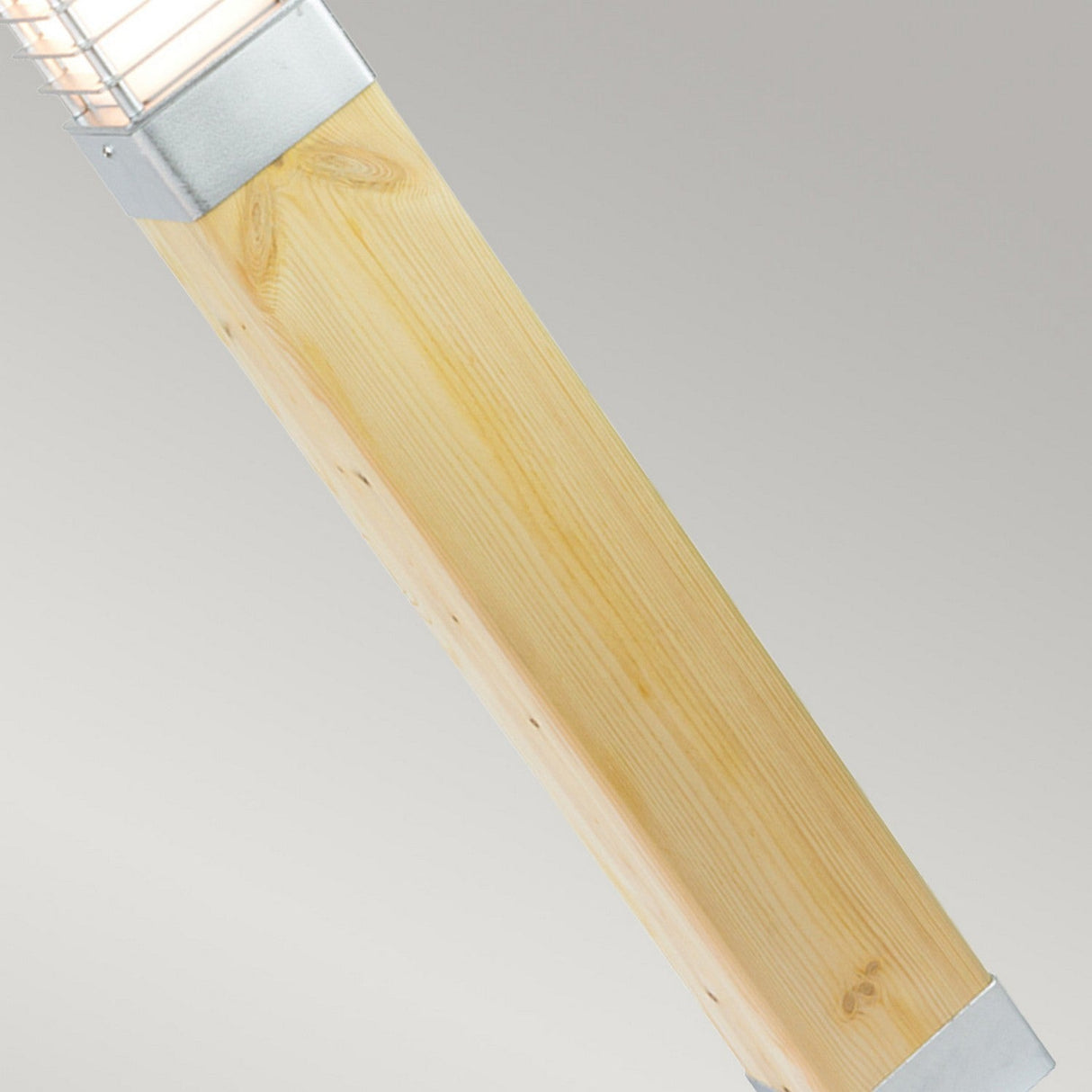 A close-up view of a wooden beam, reminiscent of the Halmstad Large Bollard Natural Wood - Silver, features a slatted metal panel along its top edge. The natural wood grain pattern beautifully complements the ventilated metal, exemplifying modern outdoor design. A neutral gray background further enhances its sleek aesthetic.