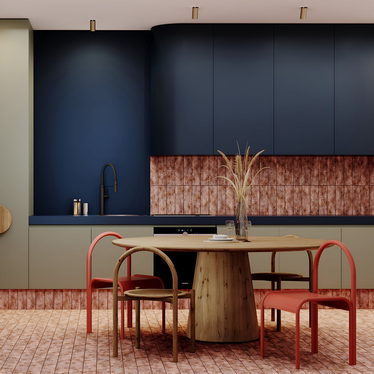 A modern kitchen features dark blue cabinets and a patterned backsplash illuminated by Focus S Single Recessed Spotlights in black. A round wooden table with four red chairs centers the room, topped with a vase of dried plants, while black-patterned tiles finalize this minimalist look.