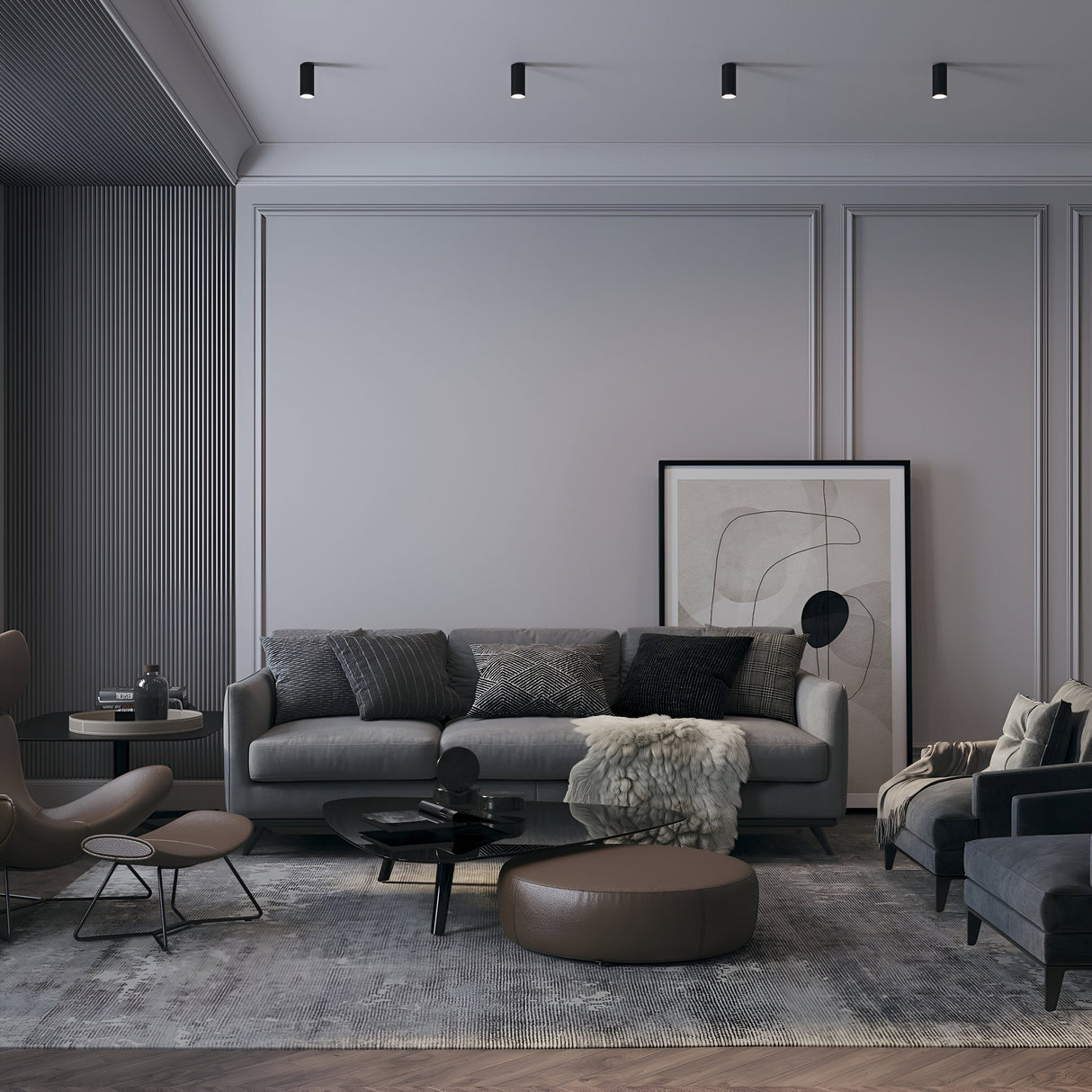 A modern living room includes a gray sofa adorned with multiple cushions and an abstract art piece framed against the wall. A round ottoman, two dark chairs, and a patterned rug add to the ambiance, while fixed illumination from Focus S Fixed Round Surface Mounted Downlights - Black highlights the wainscoted walls.