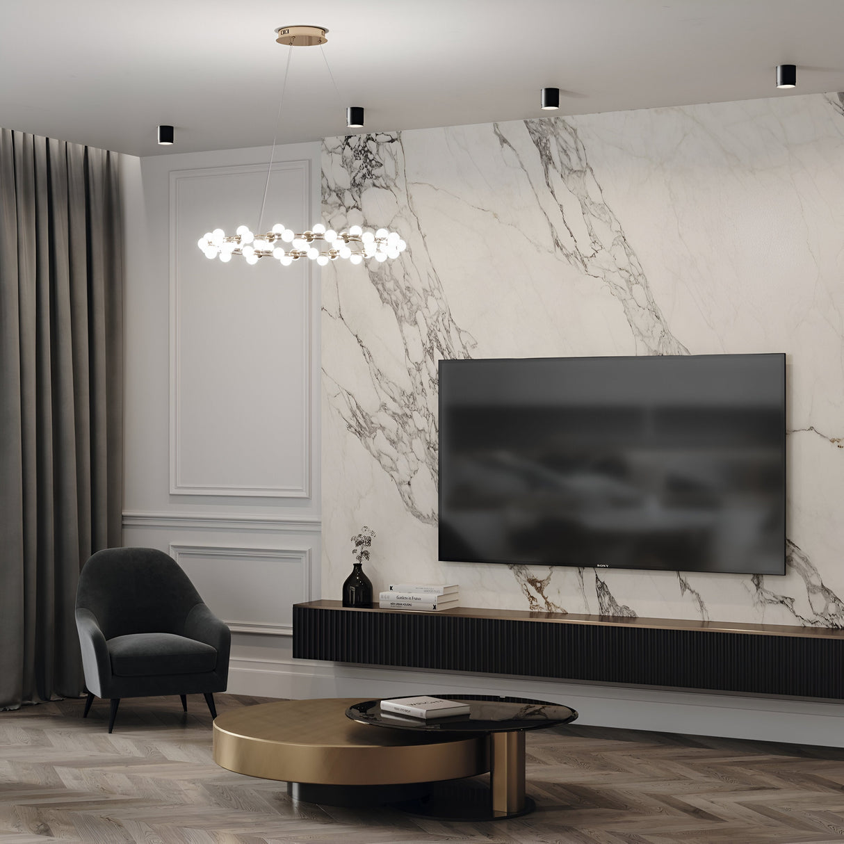 A modern living room features a large flat-screen TV on a marble accent wall, paired with a sleek black console, round gold coffee table, and dark grey armchair. Its illuminated by the Polar Round Surface Downlight - Black. Pendant lights hang above, with thick grey curtains framing the window.