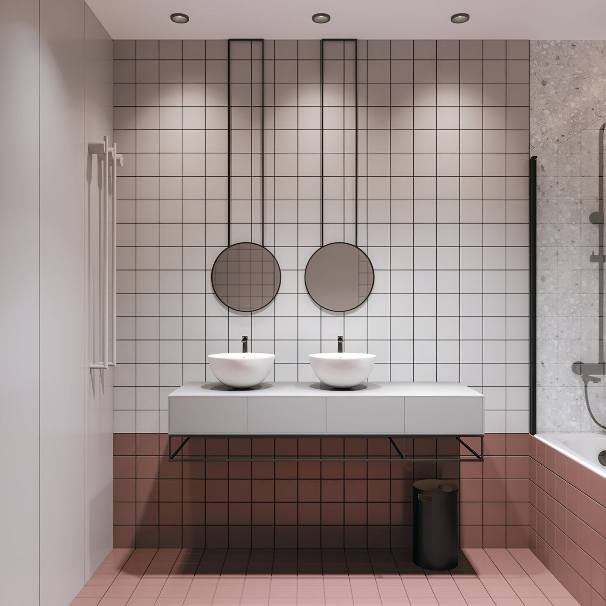 A modern bathroom features two round mirrors above white vessel sinks on a floating vanity. It is brightly lit by a Zoom Single Fixed Round Recessed Downlight - Black, and showcases white square tiles with a pink border. The floor echoes the pink tiles, and theres a shower area on the right with a glass partition.