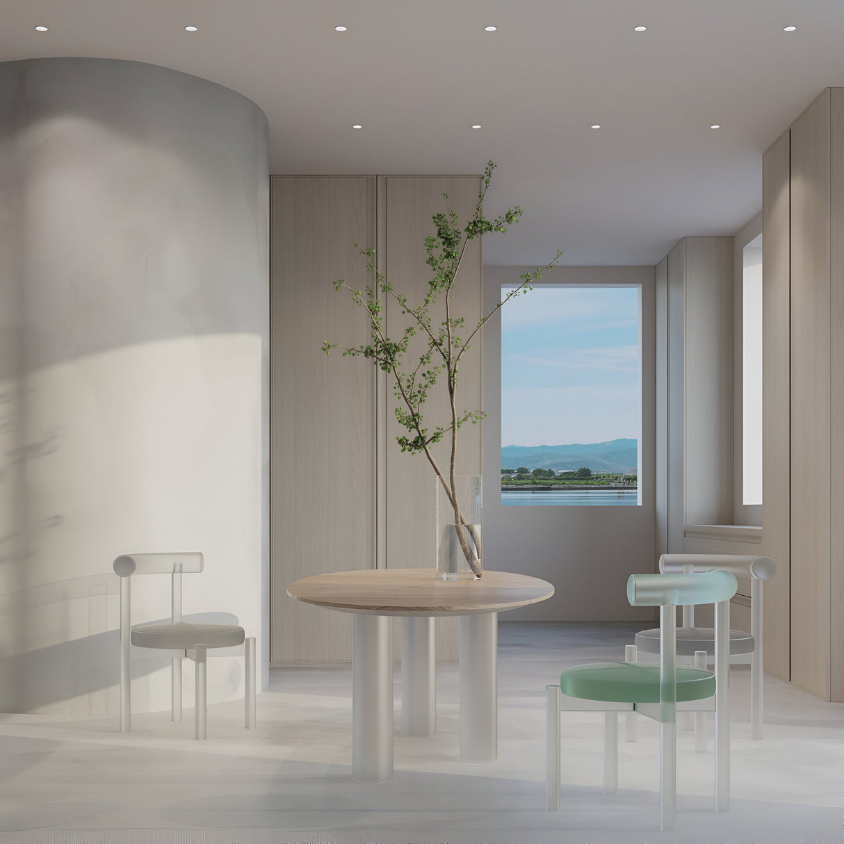 A minimalist space features a round wooden table, three modern chairs, and a vase with branches. The serene ambiance is enhanced by Reif Round Recessed Downlights - White. A large window offers views of mountains and water, while light wood paneling adds warmth to the room.