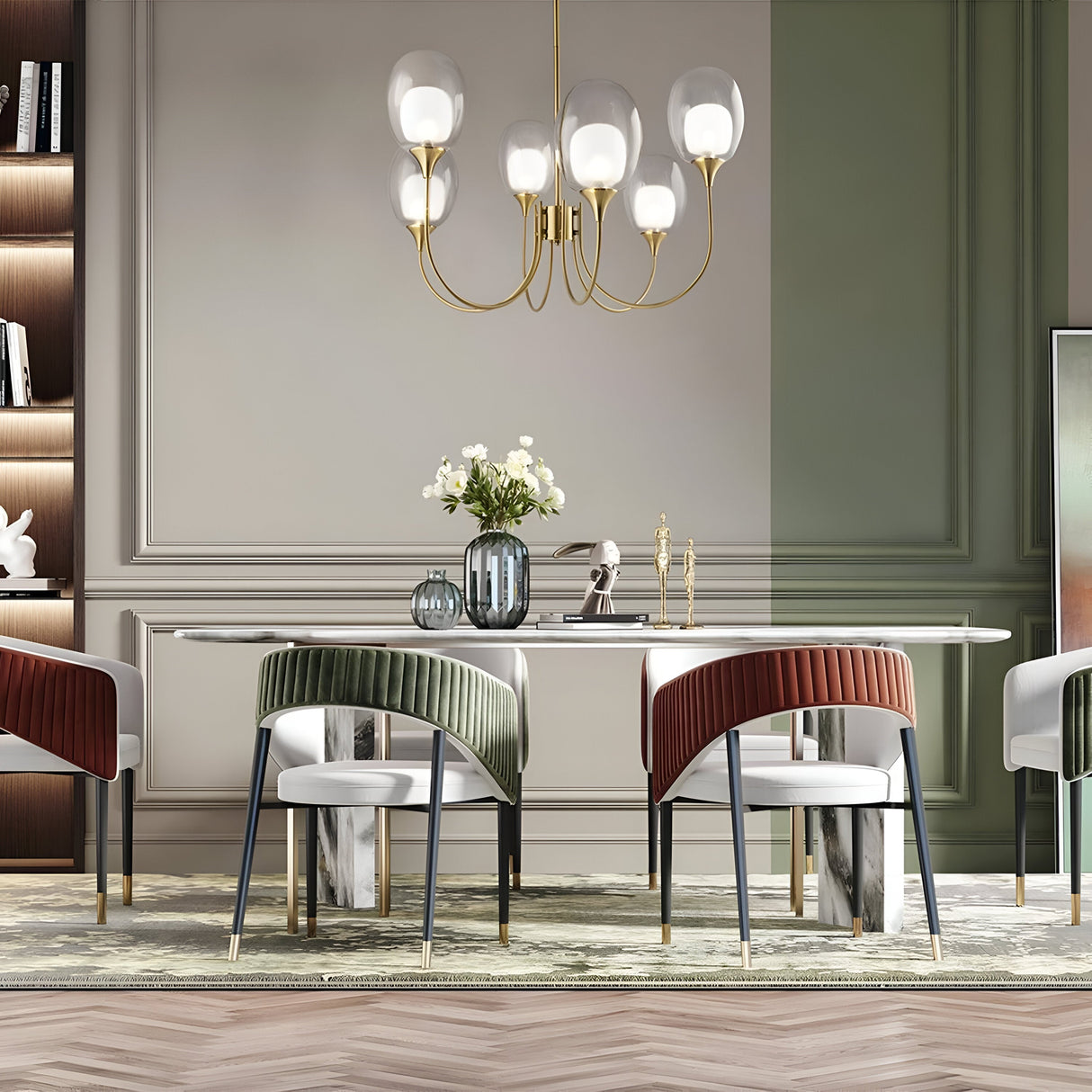The modern dining room showcases a sleek table with stylish green, red, and white chairs. Above, the Aura 6 Light Chandelier in brass featuring globe-shaped bulbs hangs centrally. A vase with white flowers complements the elegant wood paneling in the neoclassical design.