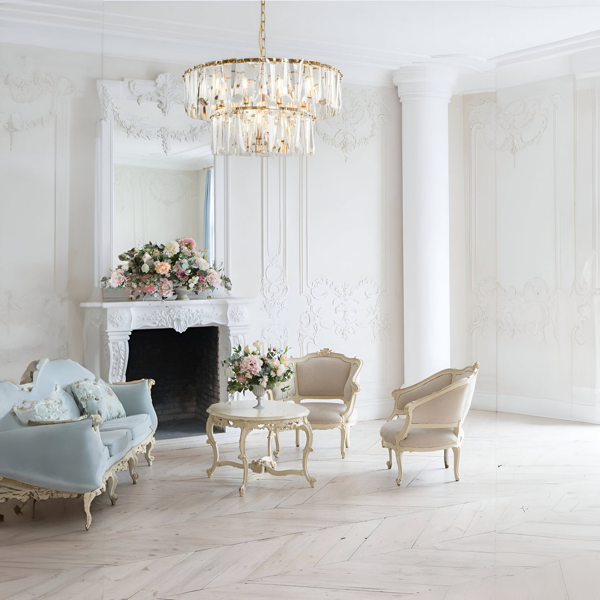 A beautifully elegant room with ornate furniture, featuring the Puntes 12 Light Chandelier in gold. A large mirror sits above a white fireplace adorned with pink and white flowers. Includes a pastel blue couch and cream chairs around a table, creating a classic, luxurious ambiance.