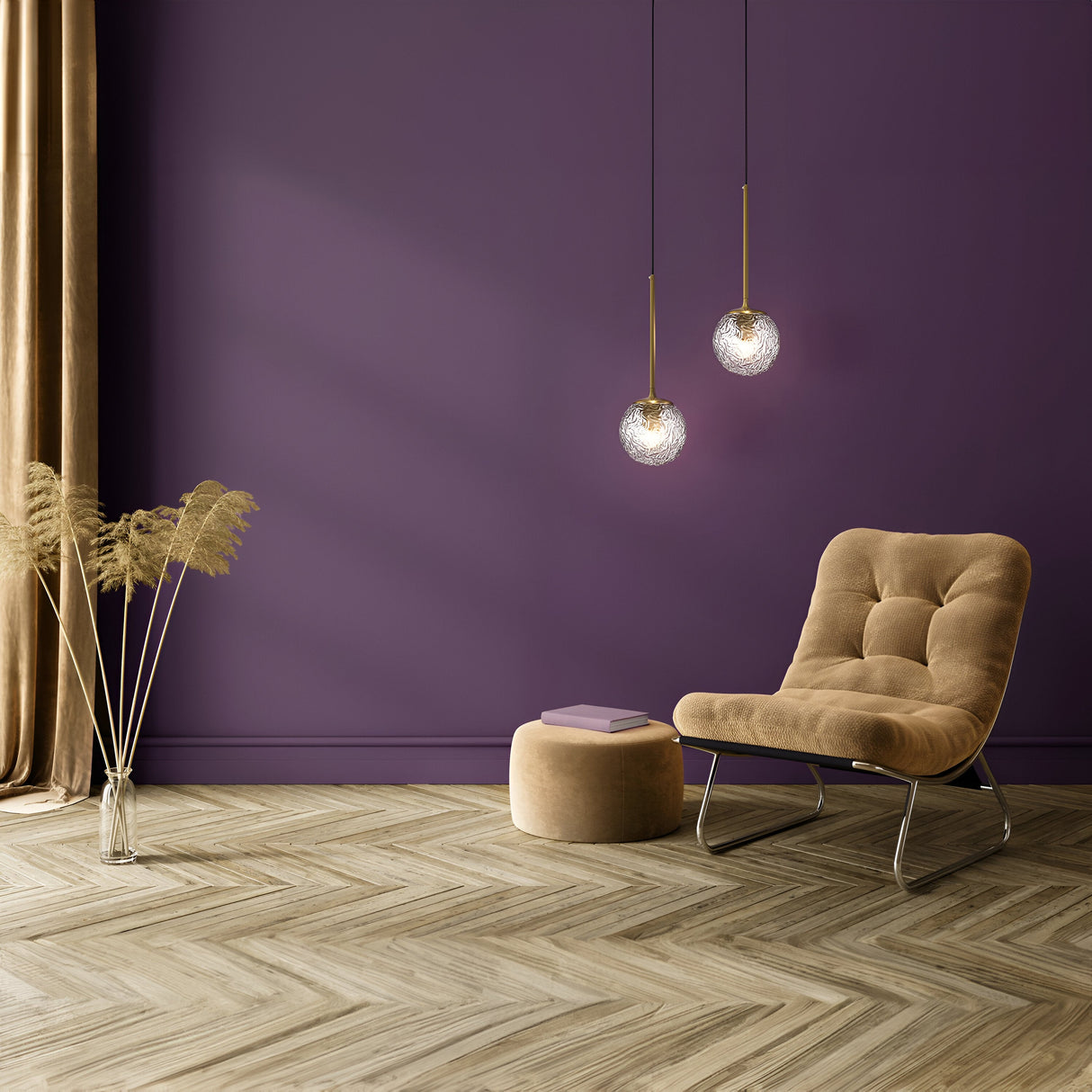 A cozy room with a purple wall features a beige cushioned chair and pouf. Two Ligero Pendant Lights - Brass With Clear Moire Glass hang above, casting a warm glow. A glass vase with pampas grass sits near beige curtains on the herringbone wood-patterned floor, adding charm to the ambiance.
