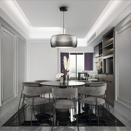 Elegant dining room with a round glass table, eight gray chairs, and the Solen LED Pendant featuring a black glass dome with raindrop effect. The walls have decorative molding enhanced by purple curtains. Minimalist shelving on the right adds an industrial touch.