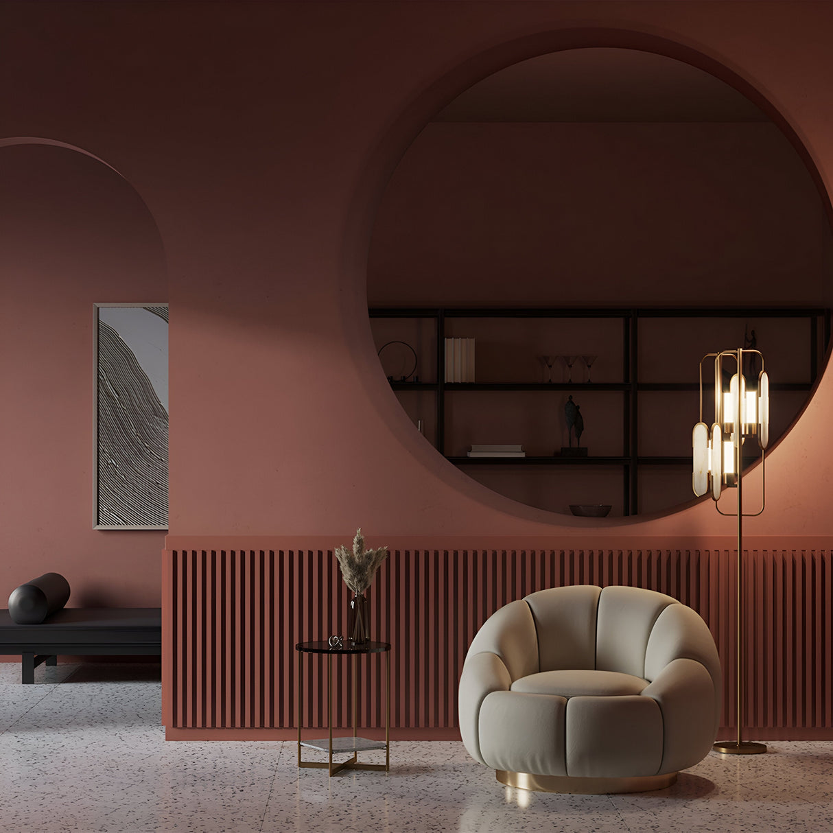 A modern interior features terracotta walls, a large circular mirror, and a beige armchair. The Marmo 2 Light Floor Lamp - Brass adds elegance. A small table with a vase sits near the dark bench with a rolled cushion, while shelving displays decor on the back wall.