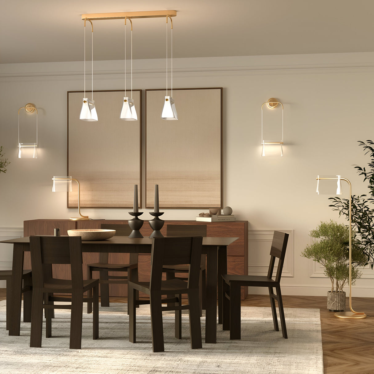 The modern dining room features a dark wooden table set for four with black candlesticks, two large wall panels above a sideboard, and sustainable elegance with the Cabaret LED Table Lamp in brass. Energy-efficient pendant lights, a rug, plants, and wooden flooring complete the decor.