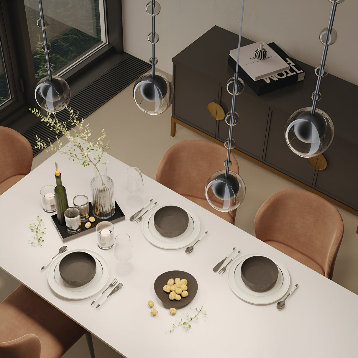 A modern dining table set for four features black and white dishes, cutlery, and glassware. A black tray holds a wine bottle and cocktail shaker under the Ros 1 Light Pendant with a clear glass shade for an elegant touch. The sideboard in the background showcases decor and a magazine.