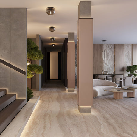 A modern hallway with sleek beige columns and recessed lighting leads to a stylish space. The light marble floor complements contemporary furniture and decorative plants, including trees. A minimalist dining area features the Glassy Ceiling Flush Light with smoky black glass in the background.