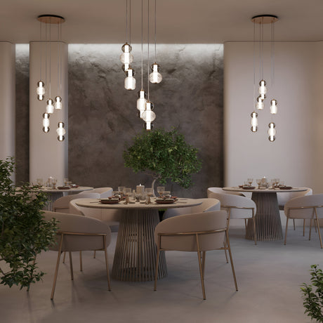 A modern dining room showcases circular tables with sleek, light-colored chairs. The Drop LED Cluster Pendant Light 80W 3000K - Chrome efficiently illuminates the space, while green potted plants add a natural touch against the textured gray walls.