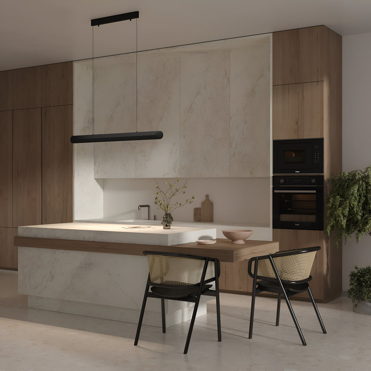 A modern kitchen showcases a minimalist design with marble countertops and wooden cabinets. The Motion LED Dimmable Linear Suspension Light in black illuminates two black chairs with woven seats. A potted plant, bowl, and wooden decor on the island enhance the cozy ambiance.