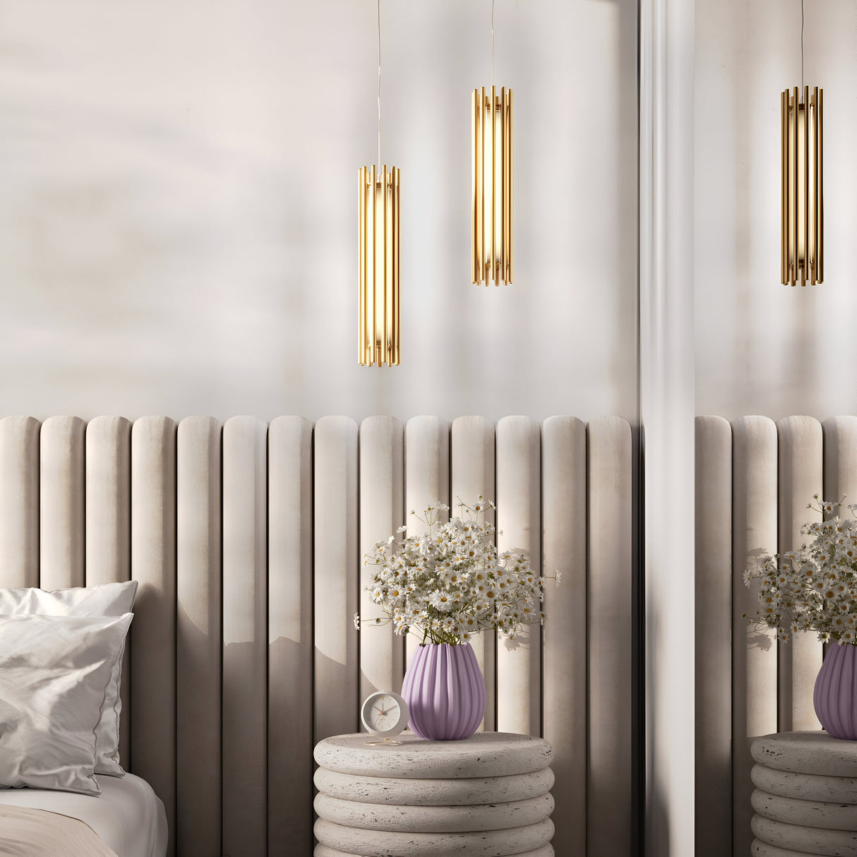 A minimalist bedroom features a Sonata LED Pendant Light 3000K 12W - Brass, a cushioned headboard, and a round side table with a purple vase of white flowers. An analog clock sits by the vase, while soft cushions adorn the bed.
