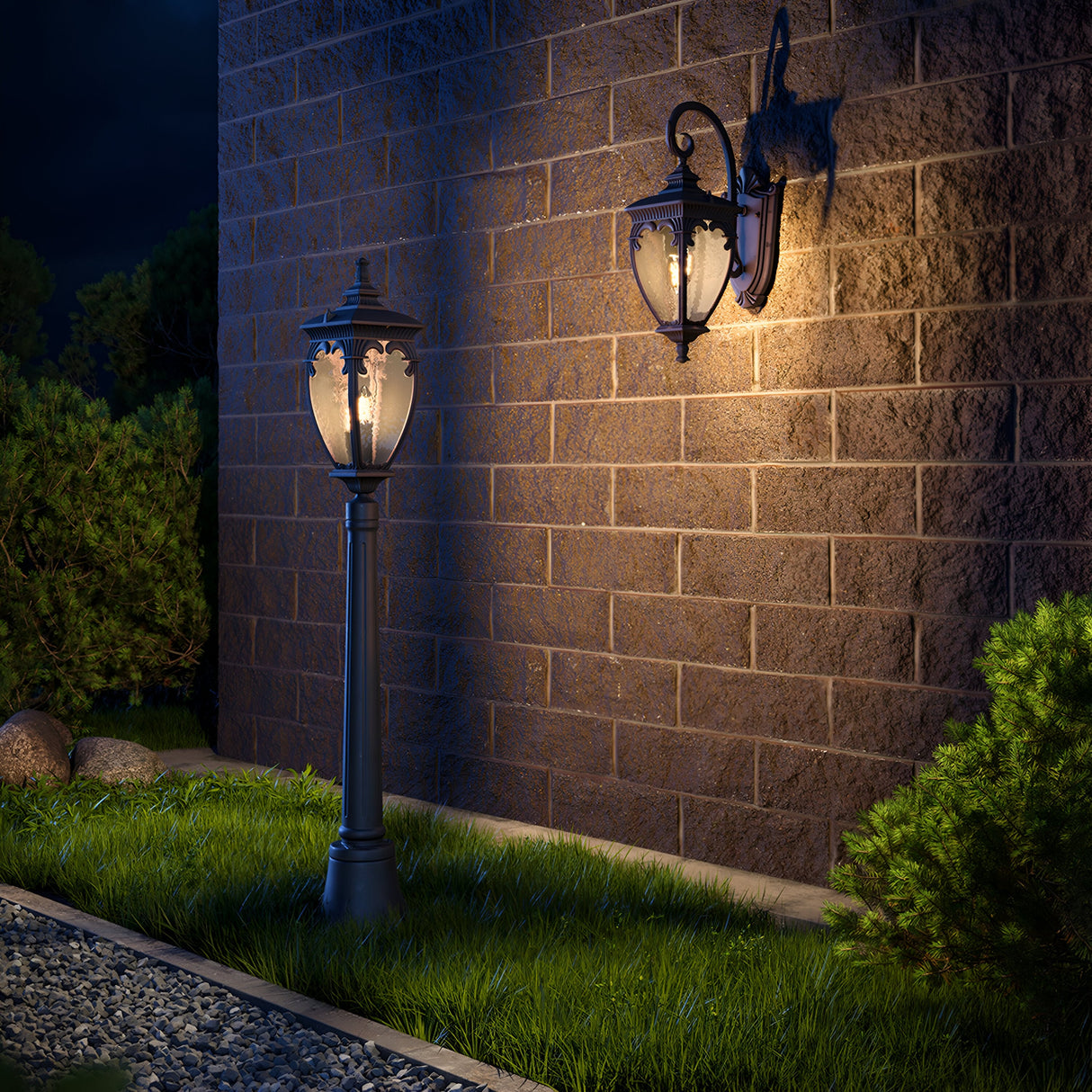 The Fleur 1 Light Pillar Lantern - Bronze mounted on a brick wall and an outdoor lamp post illuminate a garden scene at night. This weather-resistant aluminum light casts soft shadows on the grass and nearby shrubs, enhancing the peaceful ambiance.