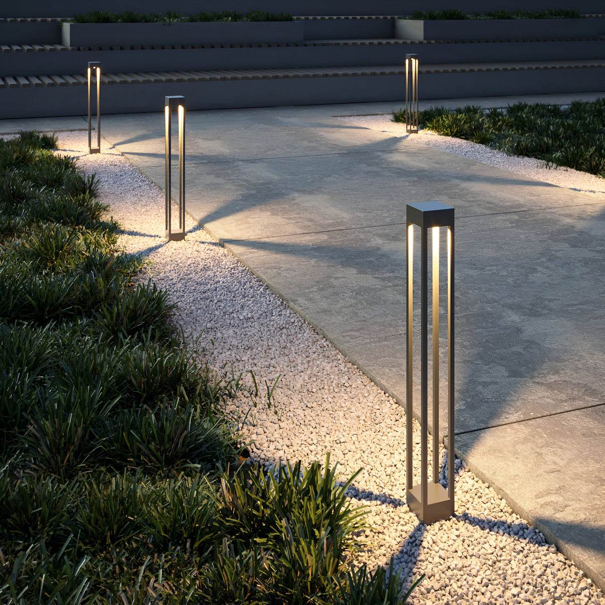 The modern pathway glows warmly with Elbe Bollard Light 100cm in Graphite, illuminating gravel and stone. Sleek metal enhances the contemporary look as steps lead through the neatly trimmed lawn to an elevated area.