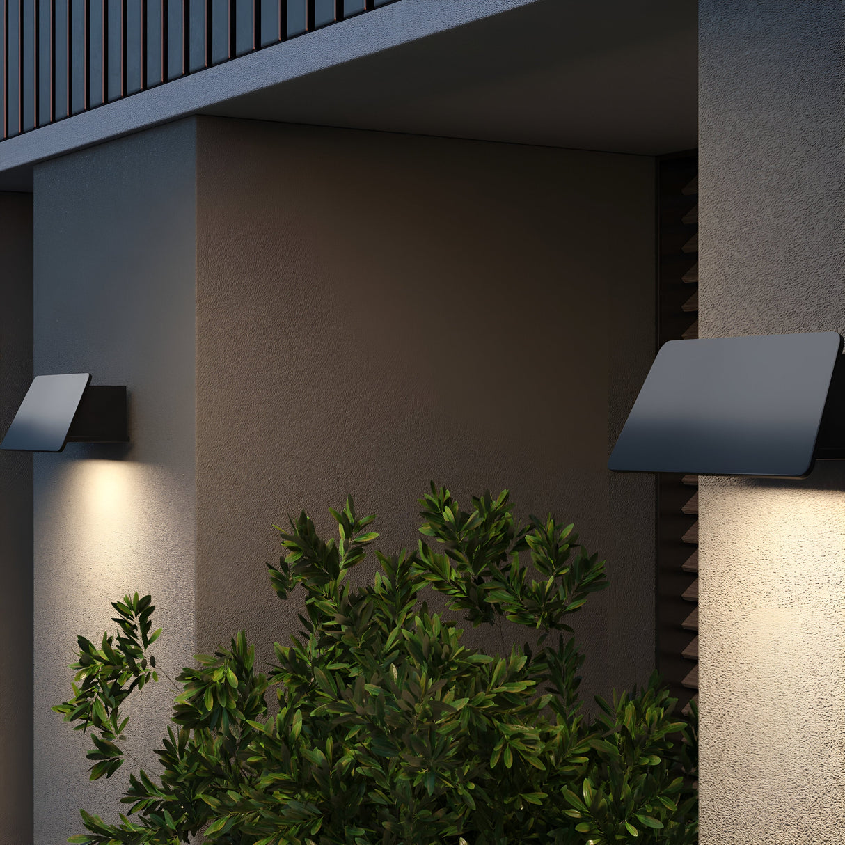 The modern buildings exterior features square Trupp Outdoor Wall Lights, graphite-finished for elegance, illuminating a green bush. With an IP54 rating, these 6W 3000K lights showcase a minimalist design with clean lines.