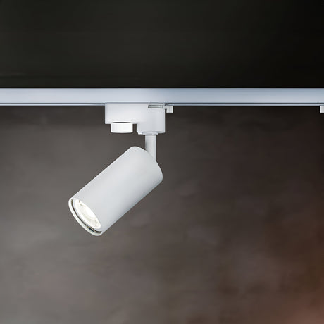 A close-up of the white Focus Mini Single Phase Unity Track Spotlight against a dark background shows the cylindrical light attached to a horizontal track, angled downward for accent lighting.