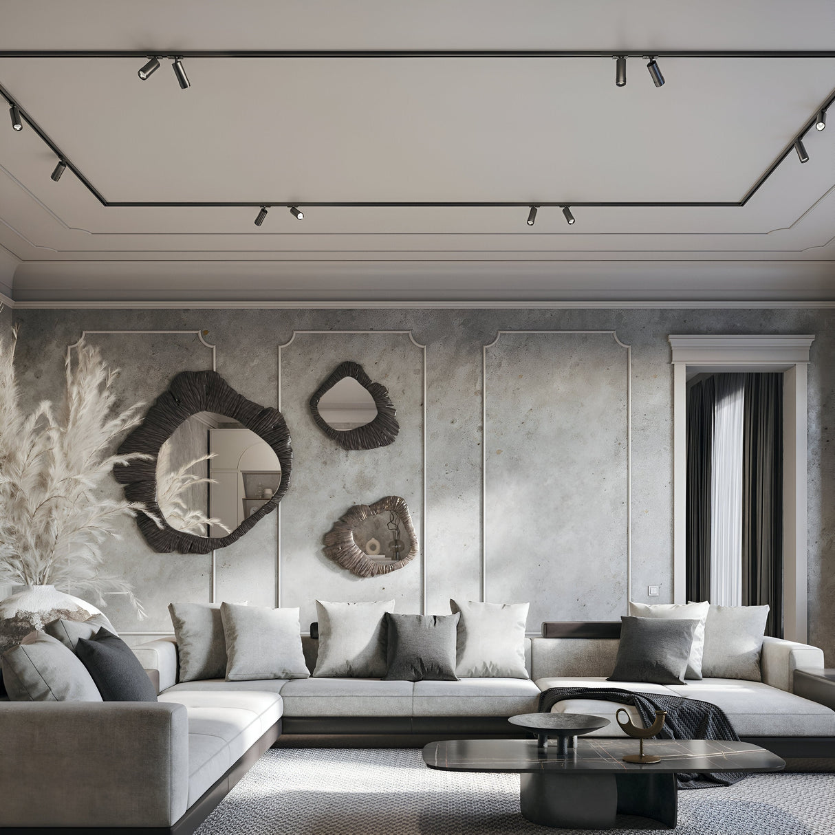 A modern living room features a large gray sectional sofa, decorative pillows, and a black coffee table. Abstract mirrors and art pieces are illuminated by the Focus Zoom LED Single Phase Unity Track Spotlight 12W 3000K - Black. Dried pampas grass adds charm to one corner.