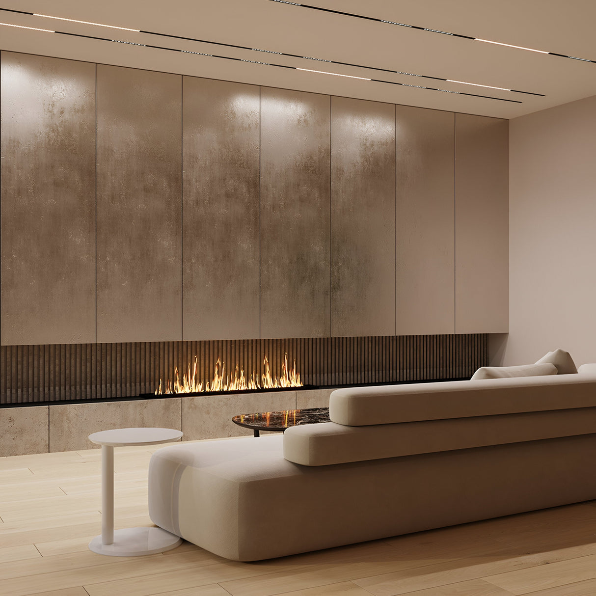 A modern living room boasts a minimalist design with a sleek LED linear fireplace in a textured wall. A large beige sectional sofa faces the fire, while light hardwood floors and discreet Points LED Linear Track Lights for Magnetic Exility create ambiance. A small round table completes the cozy setup.