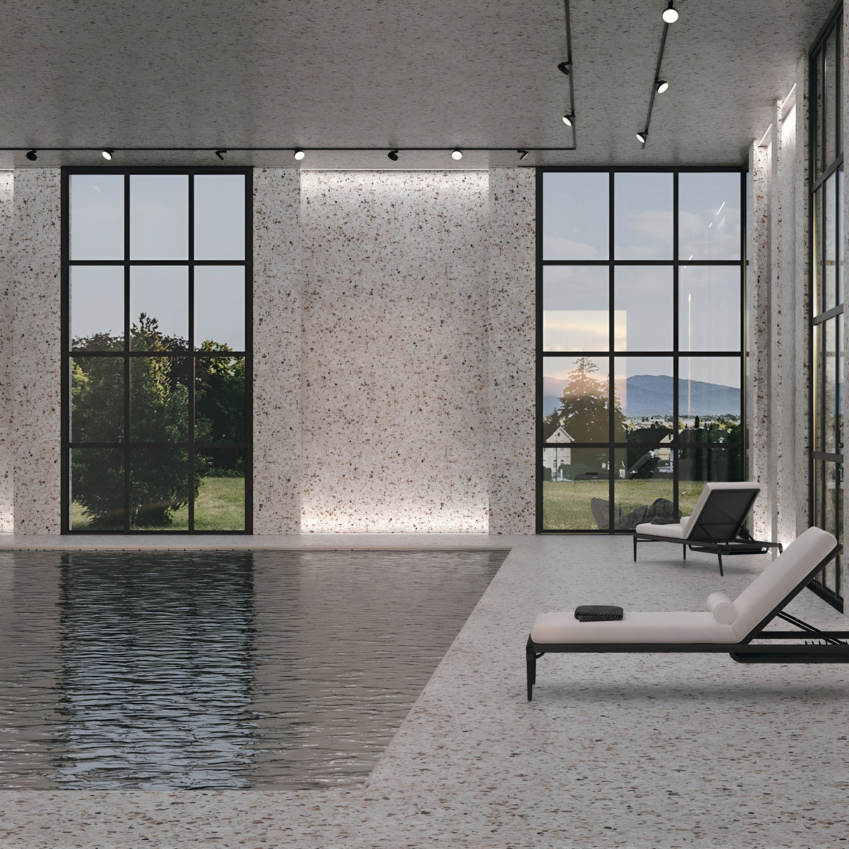 The indoor pool area features large floor-to-ceiling windows with tree and hill views. Two white loungers complement the minimalist terrazzo flooring and walls. Modern lighting, including Zon LED Single Phase Unity Track Spotlights 12W 4000K in black, adds a sophisticated touch.