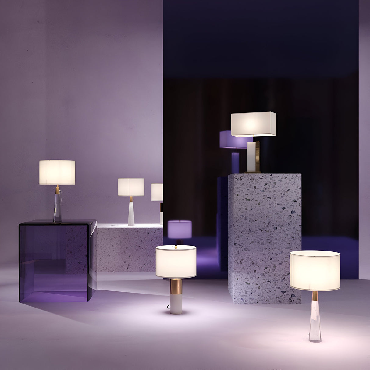 A modern showroom exudes elegance, featuring a range of lamps with sleek metal and glass bases, including the Bianco Table Lamp—Brass & Alabaster with a white round shade. These are showcased on purple-tinted glass tables and stone pedestals against light purple and dark-toned backdrops.