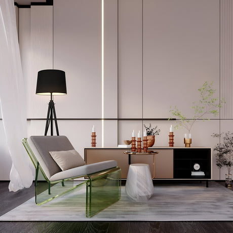 The modern living room features a transparent green chair, a gray cushion, and sleek design. A Calvin Floor Lamp - Black With Natural Wood Tripod stands beside a cabinet adorned with candles. Minimalist walls and white sheer curtains are accentuated by industrial décor lighting for style.