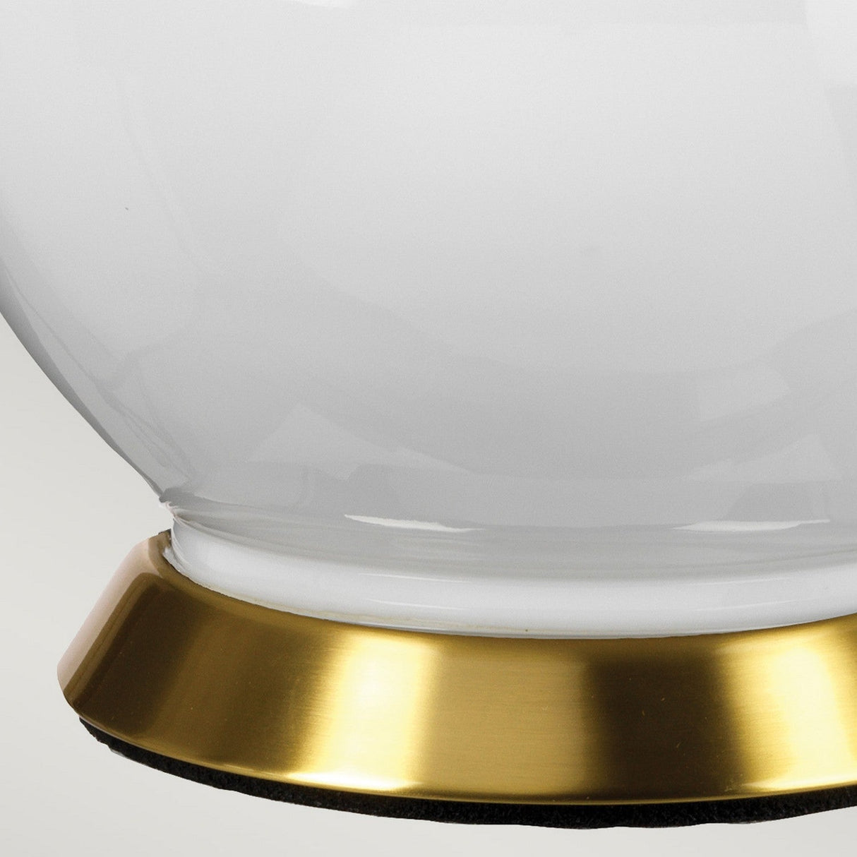 Close-up of the lower part of a white ceramic vase with a reflective surface, resting on a round, shiny gold base. This sophisticated combination evokes the minimalist charm of the Isla 1 Light Table Light in White/Green, adding a sleek design to any decor against a plain background.