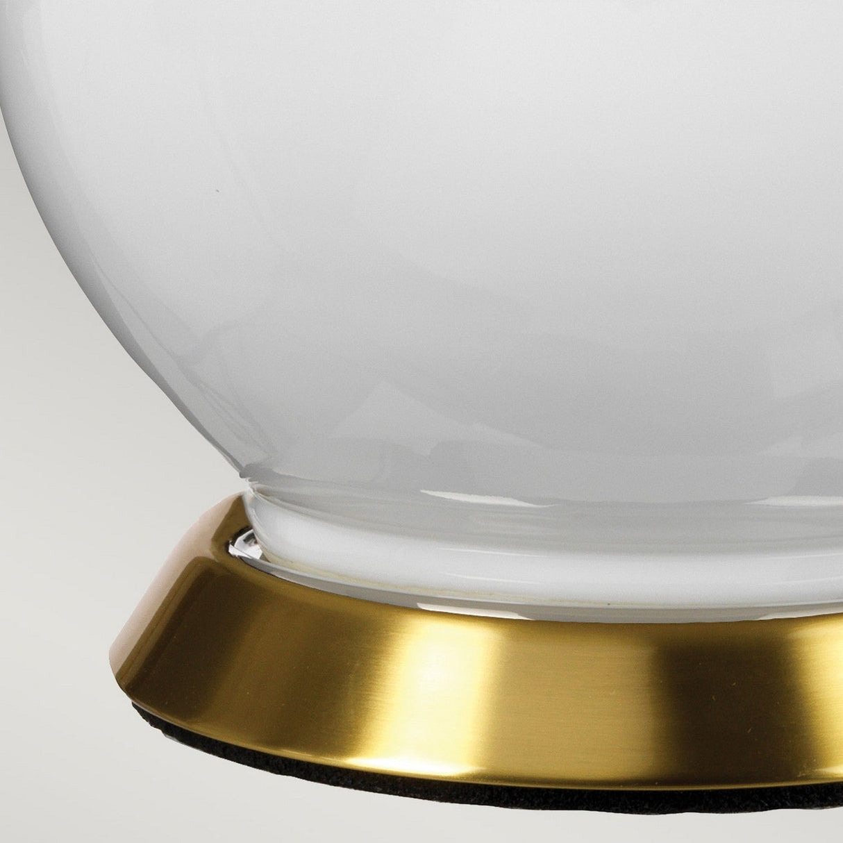 Close-up of the Isla 1 Light Table Light with a round, white ceramic base featuring a light pink accent, set against a light gray background.