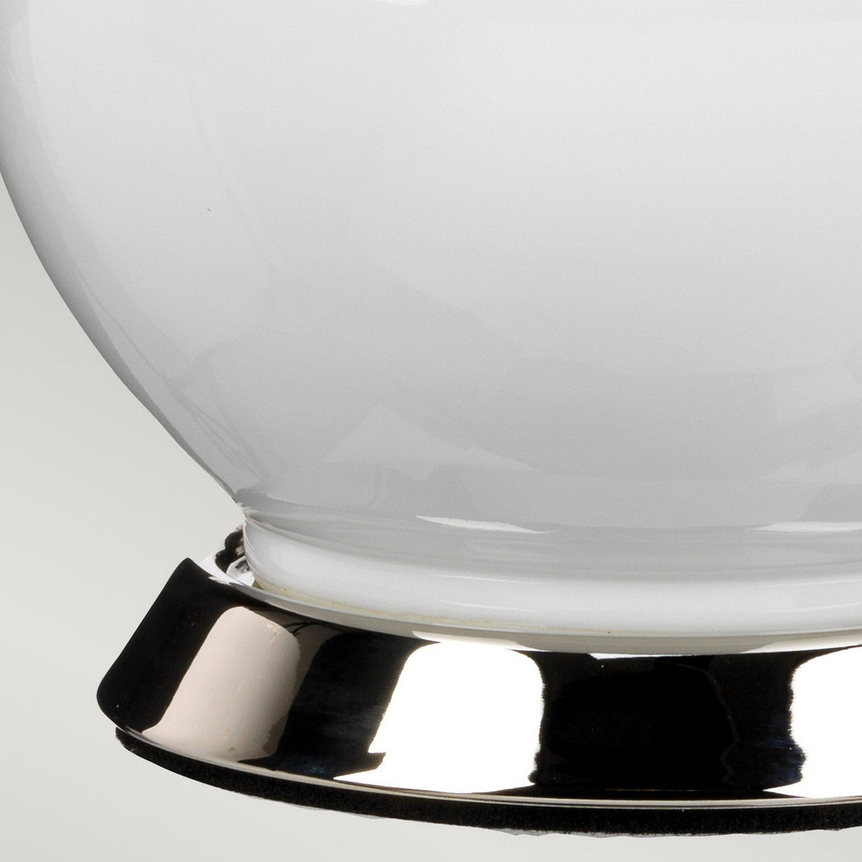 Close-up of the Isla 1 Light Table Light in white and teal, featuring a modern glossy metallic base complemented by a sleek ceramic finish. The fixture's smooth, opaque surface contrasts with the shiny, reflective metal.