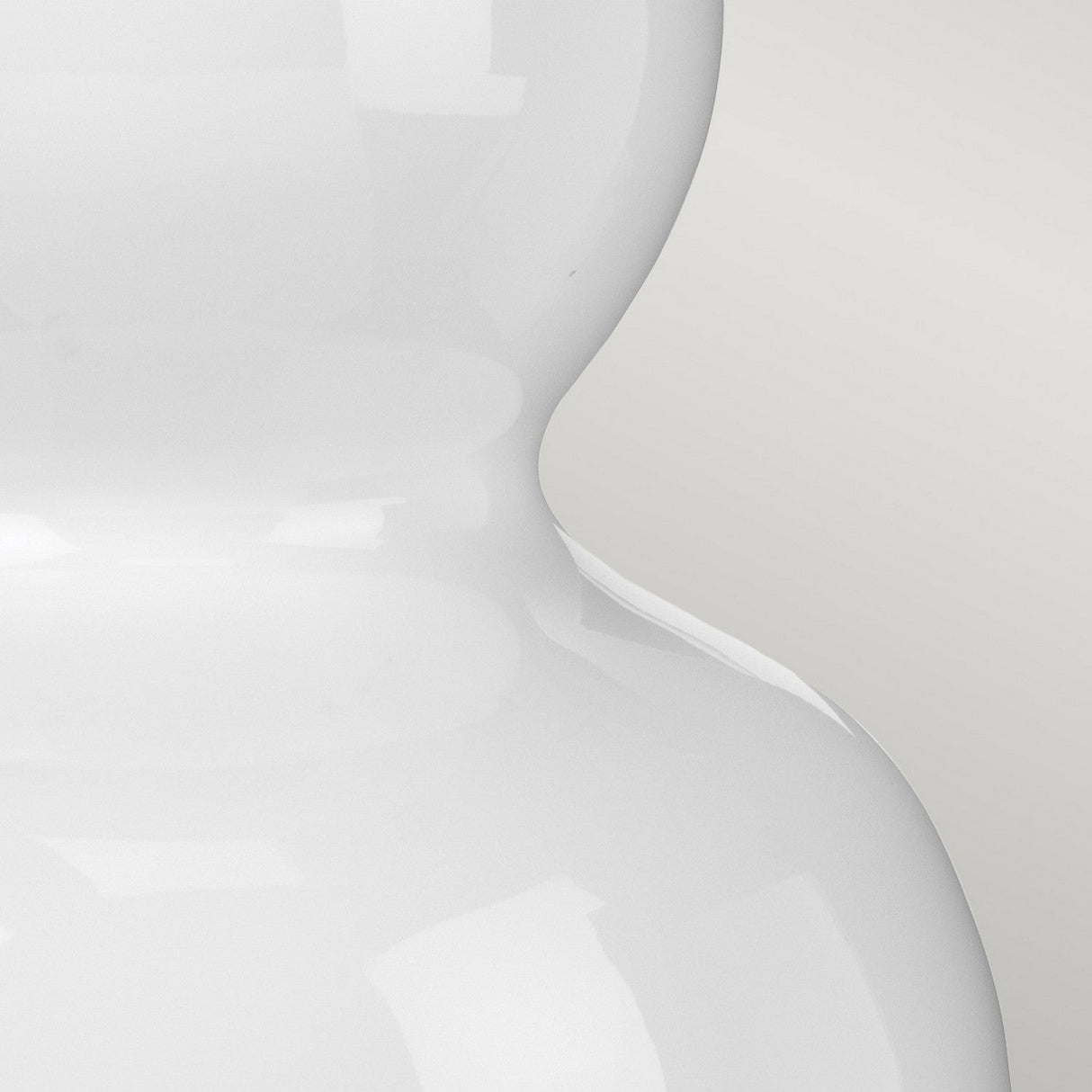 A close-up image of a glossy white ceramic vase with a curvy, smooth shape against a light gray background, accompanied by the Isla 1 Light Table Light featuring a yellow shade. The vase's shiny surface reflects light, enhancing its texture and perfectly complementing the ceramic base of the table light.
