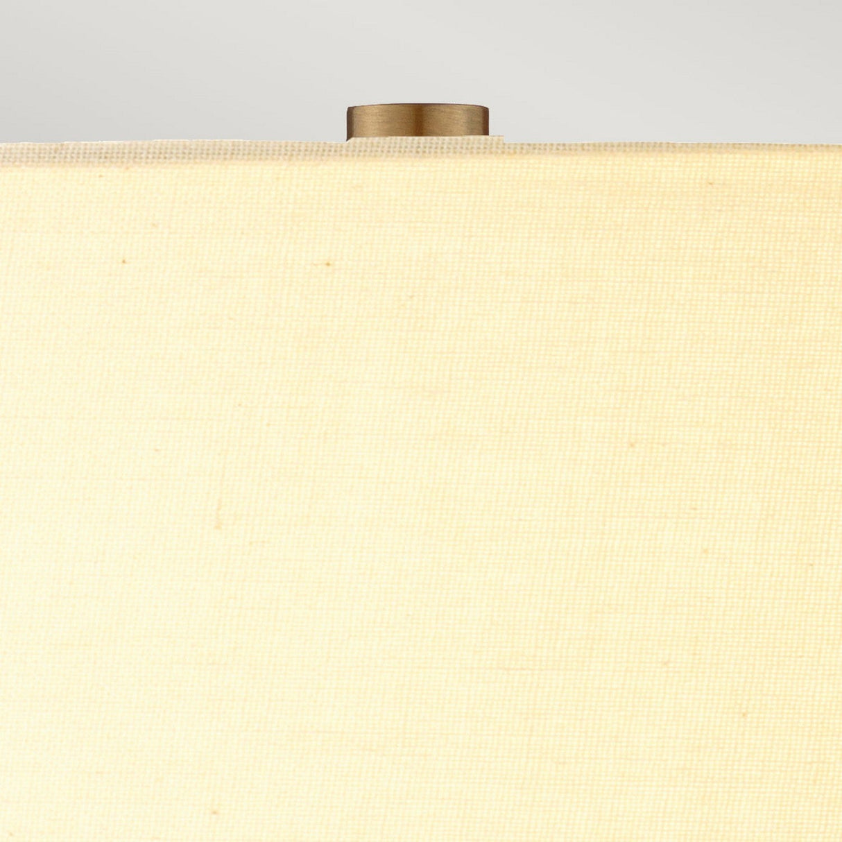 Close-up of the cream shade on the Job 1 Light Table Lamp, showcasing a brass-colored finial. The texture of the faux silk fabric is visible, with a soft gray background that enhances its elegance.