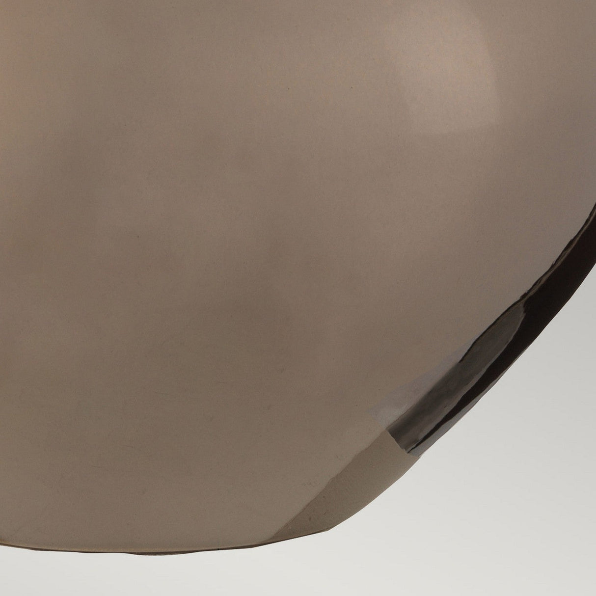 Close-up of the Job 1 Light Table Lamp with its smooth, reflective bronze metallic surface and soft brown tint, gently curving in the lower right corner against a light gray background.