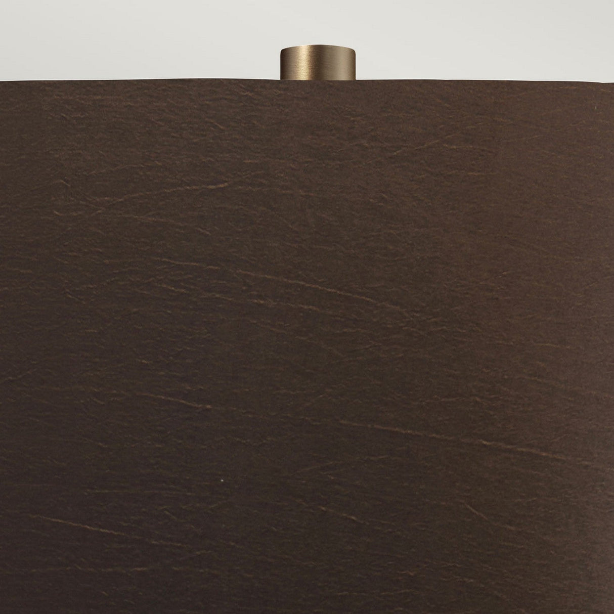 Close-up of the Job 1 Light Table Lamp, featuring a dark brown faux silk lampshade with a matte texture. A small cylindrical metallic finial is visible at the top, accentuating the bronze metallic design of the lamp against a neutral background.