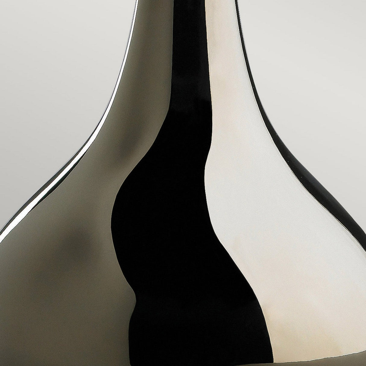 Close-up of the Job 1 Light Table Lamp in a bronze metallic finish, showcasing smooth, curving lines. The glossy black and silver appearance forms abstract, fluid shapes with high contrast between light and dark areas.