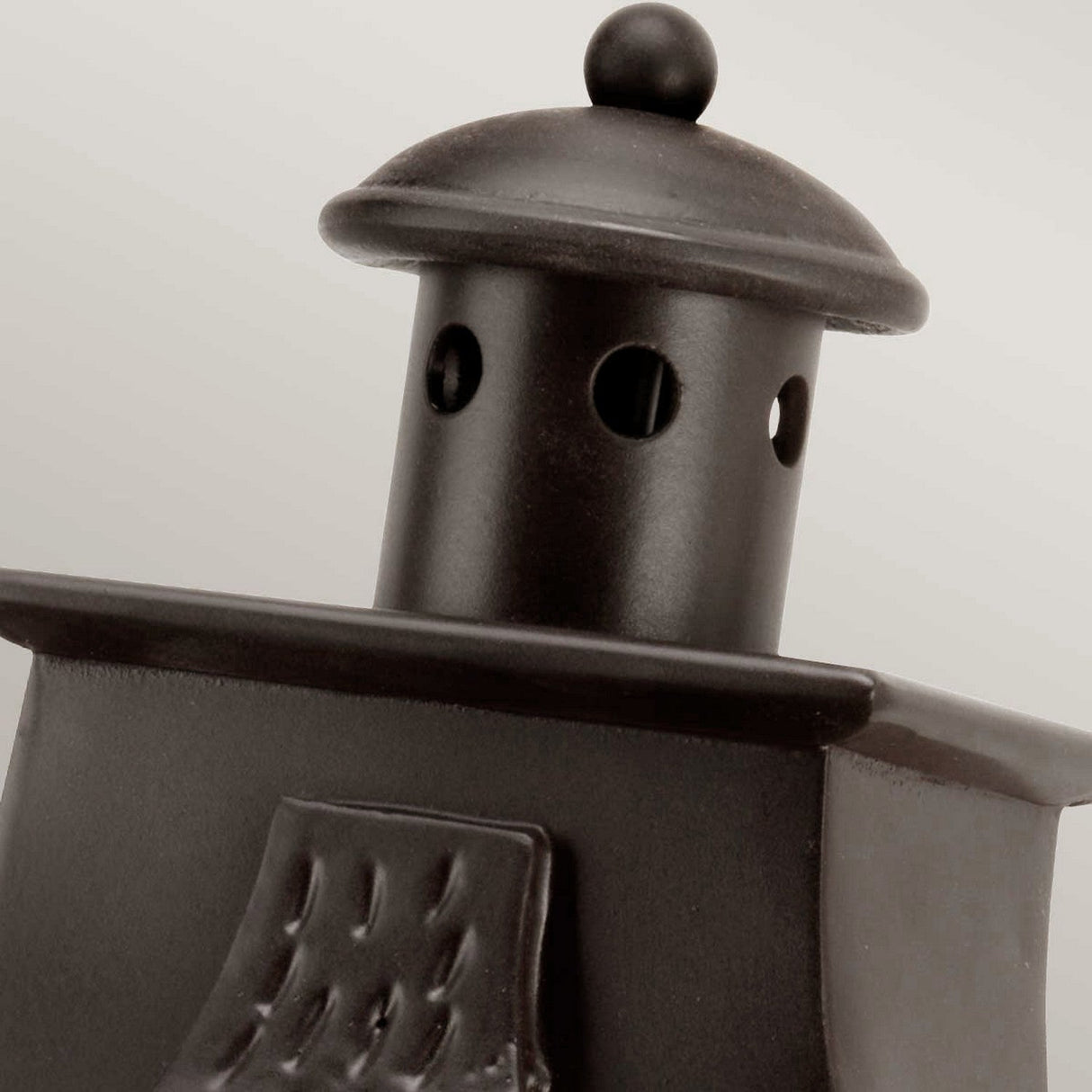 Close-up of the Kendal 2 Light Outdoor Wall Light in an old bronze finish, designed in a lighthouse shape with a round top and small circular windows. The metallic surface gleams smoothly against a neutral light gray background.