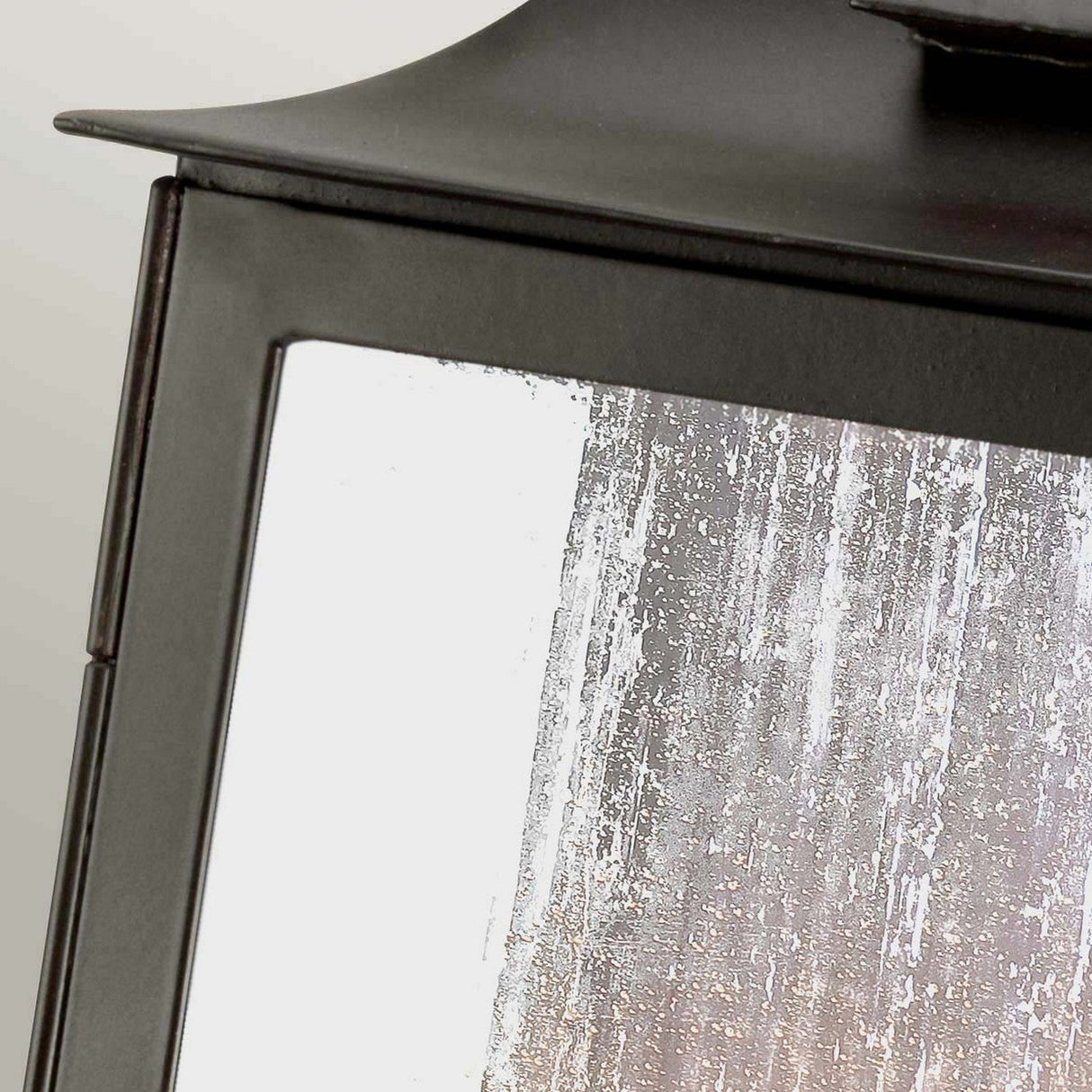 Close-up of the Kendal 2 Light Outdoor Wall Light in an old bronze finish, featuring a glass pane with a weathered, frosted appearance. The dark metal frame is slightly angled, highlighting the rustic charm of its lantern design.