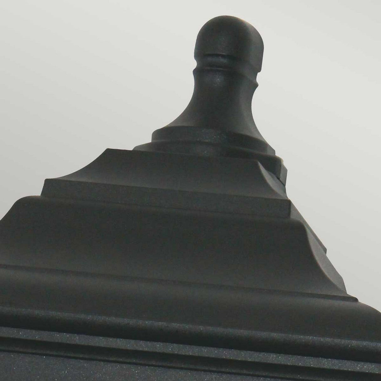 Close-up of the "Kerry 1 Light Outdoor Flush Wall Light - Black" showcasing its tiered, decorative design with a rounded finial against a neutral background, highlighting its corrosion-proof finish ideal for wall installations.