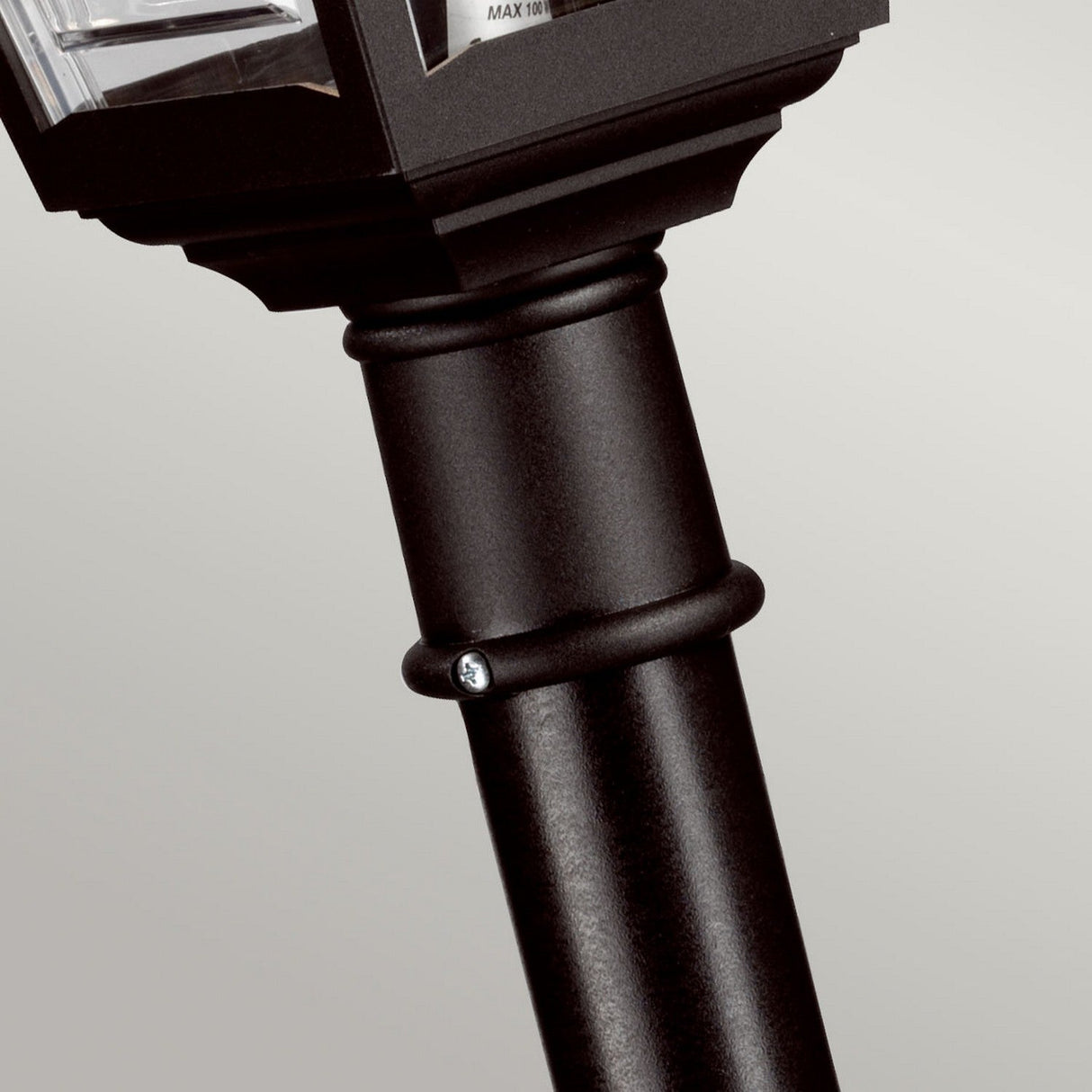 Close-up of the Kerry 1 Light Pillar Light - Black outdoor lamp post with a screw visible on the metal surface, highlighting its corrosion-proof design. The top portion of this impact-resistant lamp is partially visible against a neutral background.