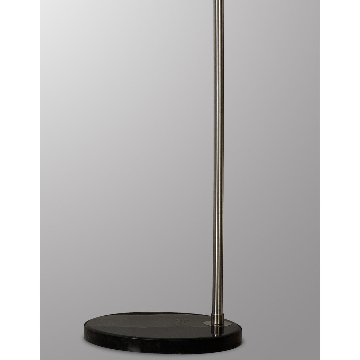 A close-up of the Kinke Floor Lamp With Hook - Black shows its round black stainless steel base and slender pole, set against a plain gray background.