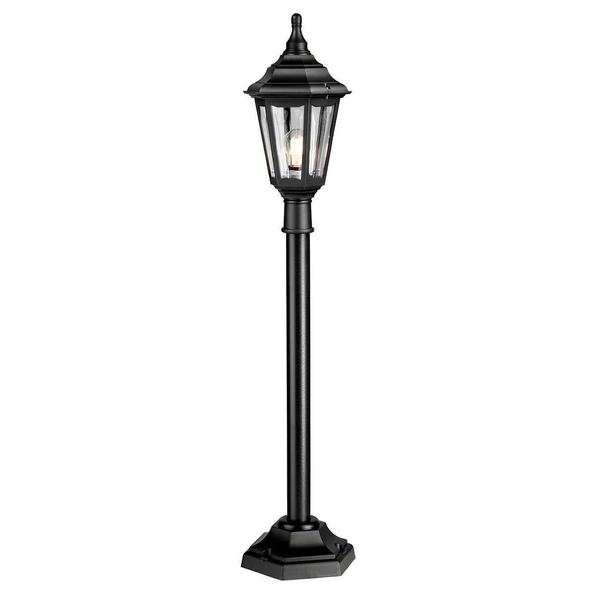 The Kinsale 1 Light Pillar Light - Black is an outdoor post light with a lantern-style design featuring a hexagonal base and clear glass panels. It showcases a decorative, traditional look with a pointed top that reveals the bulb inside, providing corrosion resistance for enduring outdoor elegance.